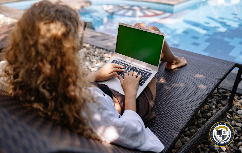 Kobieta, grafik z kręconymi włosami pracująca zdalnie na laptopie przy basenie
