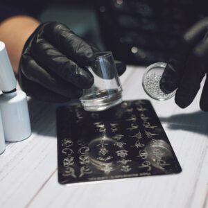 Nail Art Stamping process. Manicure master makes Stamping with nail gel polish, Stamping Plates and Transparent Stamper Scraper