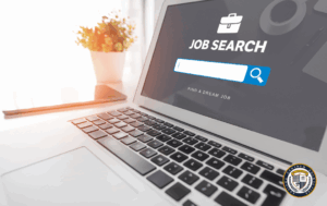 Laptop z wyszukiwarką pracy i napisem 'JOB SEARCH' na ekranie. Obok stoi doniczka z rośliną w jasnym pomieszczeniu. Szukanie pracy online z pomocą profesjonalnych narzędzi. Logo Krajowego Centrum Edukacyjnego w rogu zdjęcia