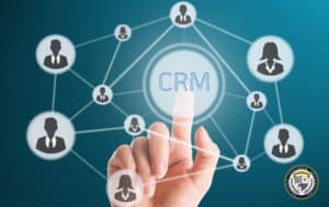 Ikonka CRM na białym tle, naokoło połączone ze sobą grafiki człowieka w kółku. Człowiek palcem klika w kółku na środku zdjęcia w napis CRM