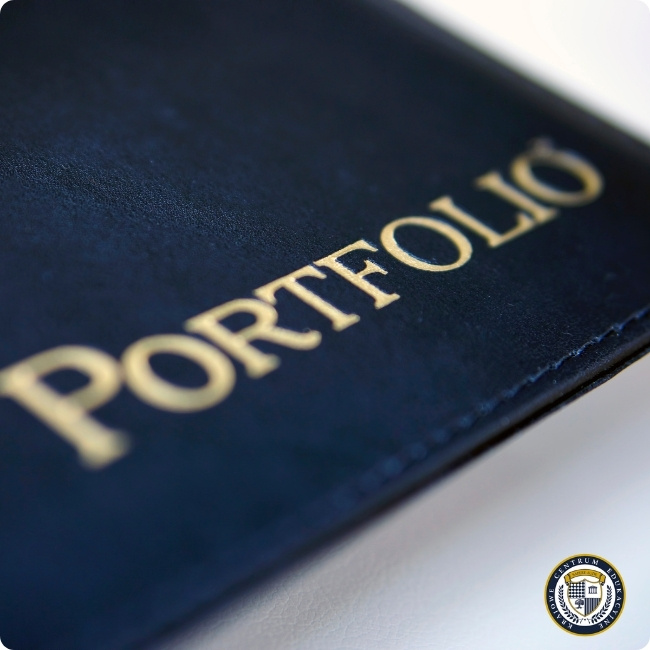 Zbliżenie na elegancką, ciemną okładkę portfolio z wytłoczonym złotym napisem „PORTFOLIO”.