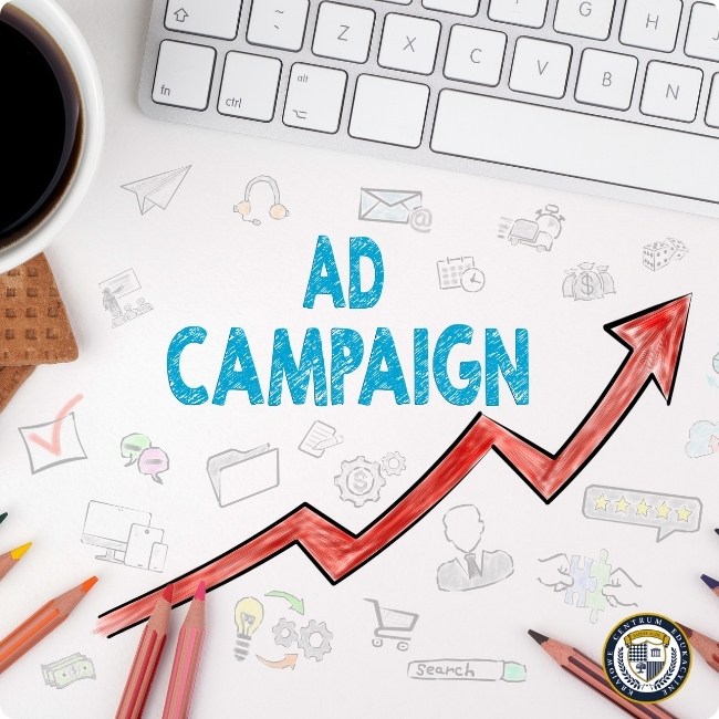 Koncepcja kampanii reklamowej z napisem 'AD CAMPAIGN' na białym tle, otoczonym ikonami marketingowymi i czerwoną strzałką wzrostu, obok klawiatury i filiżanki kawy