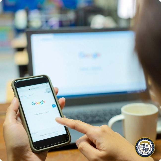 "Osoba korzystająca z wyszukiwarki Google na smartfonie, w tle laptop i filiżanka kawy - wizualizacja pierwszego kroku w Google Ads