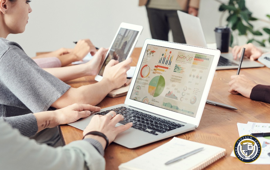 Zespół specjalistów analizuje wyniki kampanii Google Ads na laptopie wyświetlającym kolorowe wykresy i statystyki efektywności reklam. Na drewnianym stole widoczne są również urządzenia mobilne używane do monitorowania kampanii w czasie rzeczywistym