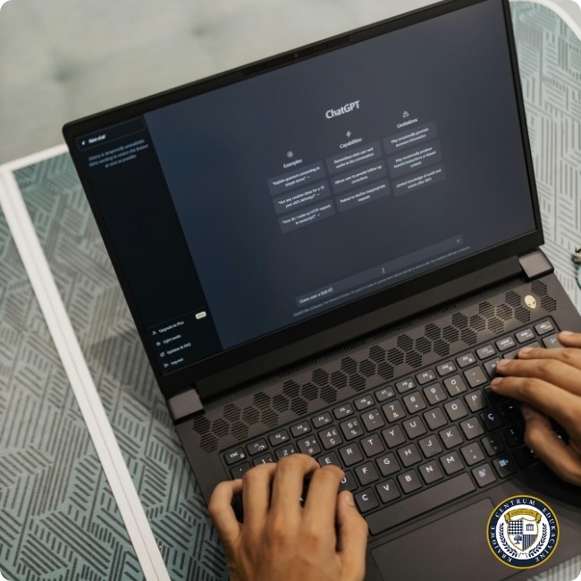 Laptop z otwartym interfejsem ChatGPT w ciemnym trybie, widoczne dłonie na klawiaturze. Na blacie z geometrycznym wzorem leży tablet. W prawym dolnym rogu logo KCE.