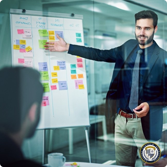 Młody biznesmen w garniturze i krawacie prezentuje tablicę z kolorowymi karteczkami samoprzylepnymi (metodologia agile/kanban) podczas spotkania w nowoczesnym biurze.
