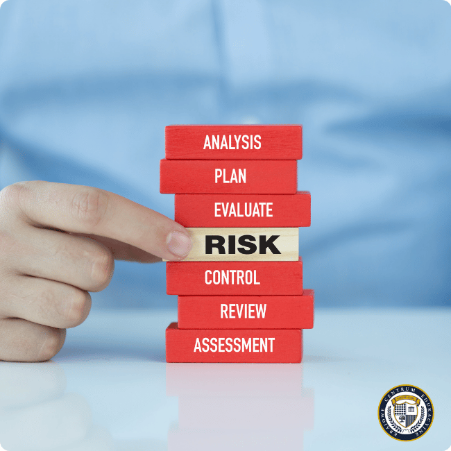 Dłoń wskazująca na drewniane klocki ułożone w stos, gdzie blok 'RISK' wyróżnia się kolorem na tle czerwonych klocków z napisami ANALYSIS, PLAN, EVALUATE, CONTROL, REVIEW i ASSESSMENT, symbolizujące etapy zarządzania ryzykiem związanym z sztuczna inteligencja zagrożenia