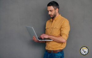 Profesjonalny specjalista SEO w żółtej koszuli analizujący dane na laptopie, pokazujący jak wygląda codzienna praca osoby zajmującej się pozycjonowaniem stron internetowych