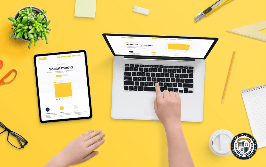 Na żółtym blacie laptop i tablet z otwartymi stronami social media, dłonie osoby piszącej na klawiaturze, roślina, okulary, notes i inne akcesoria biurowe. Dotyczy cennika Google.