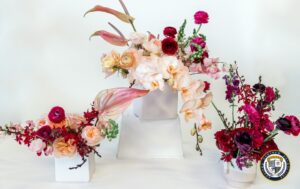 Trzy eleganckie kompozycje florystyczne w białych wazonach, prezentujące kompetencje florystyczne na najwyższym poziomie.