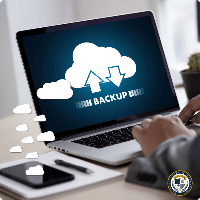 Osoba pracująca na laptopie z ekranem pokazującym proces backup - ikony chmur i strzałek 