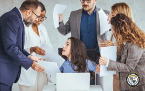 Grupa konfliktowych osób kłóci się z kobietą siedzącą przy laptopie.