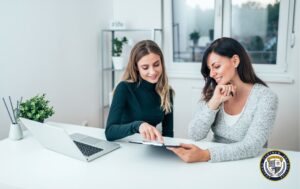 Komunikacja interpersonalna - dwie kobiety rozmawiają przy laptopie w biurze