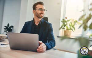uśmiechnięty mężczyzna w garniturze pracuje przy laptopie w nowoczesnym biurze