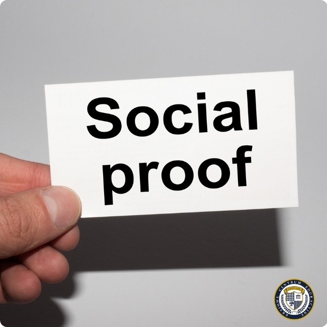 dłoń trzymająca kartkę z napisem "Social proof" ilustrująca technikę wywierania wpływu przez naśladowanie innych