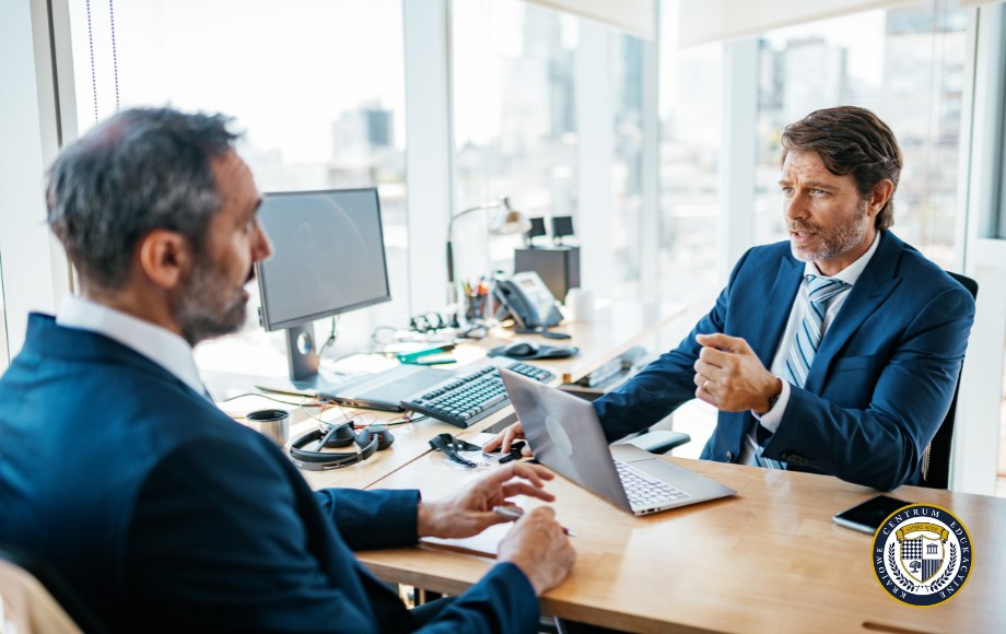 Dwóch mężczyzn w garniturach podczas rozmowy biznesowej w biurze - przykład przełamywania barier komunikacyjnych w praktyce