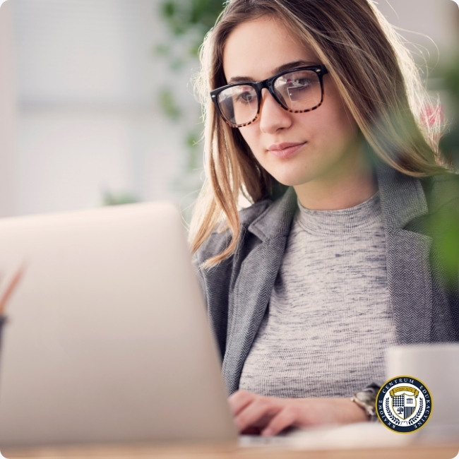 Kobieta w okularach pracująca przy laptopie - tworzenie ogłoszenia o pracę w biurze