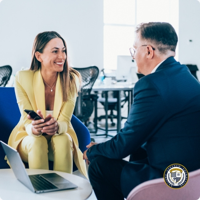 Uśmiechnięta kobieta w żółtym garniturze prowadzi konstruktywną rozmowę biznesową z mężczyzną w biurze, atmosfera otwartości i porozumienia