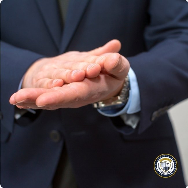 Mężczyzna w garniturze pociera dłonie w geście komunikującym oczekiwanie lub planowanie