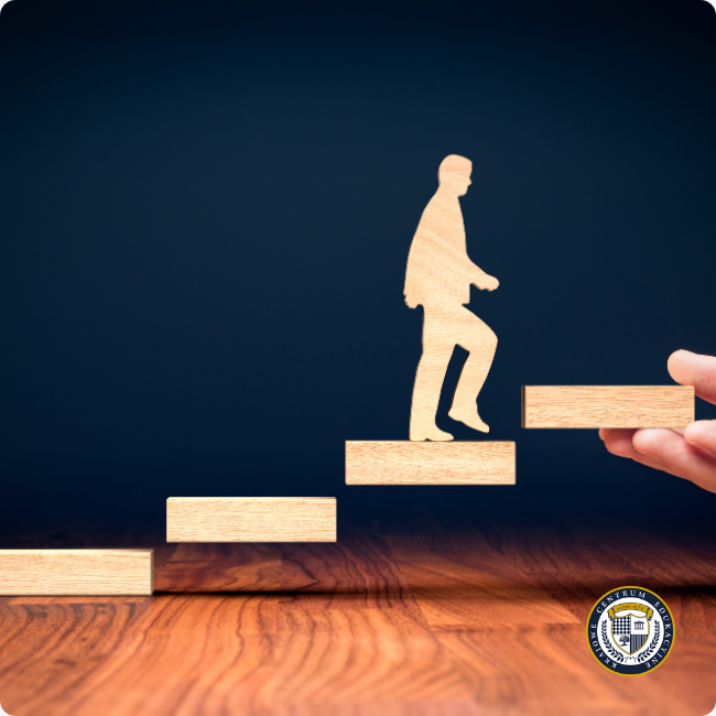 Drewniana figurka człowieka wspinającego się po schodach z klocków, symbolizująca zasadę małych kroków w automotywacji i stopniowe osiąganie celów