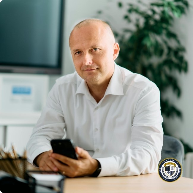 Profesjonalista siedzący przy biurku ze smartfonem - przykład pewności siebie w sytuacjach zawodowych