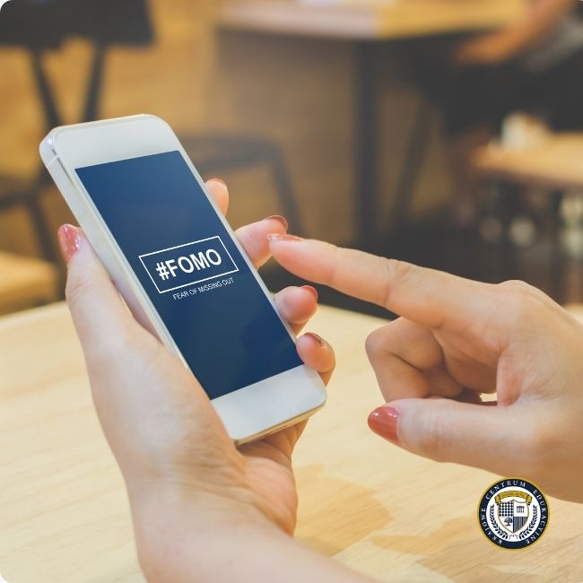 Kobieta trzymająca smartfon z napisem #FOMO.